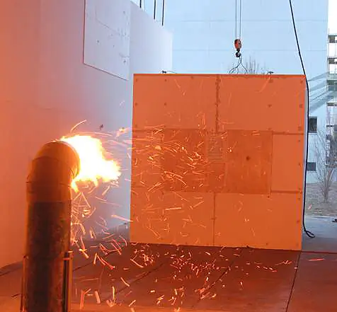 Glowing firebrands from a NIST test aimed at a fine metal screen, with a burning pad behind the mesh.